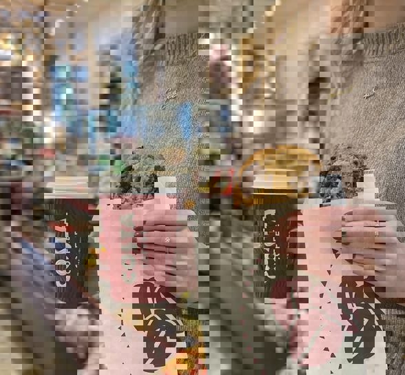 One Costa Woman Holding Coffee And Belgian Cookie Square